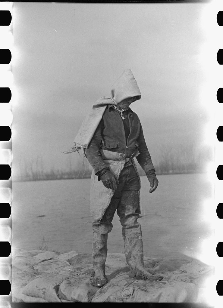 Exhausted levee workers in cold wind during flood, their bodies bent with fatigue