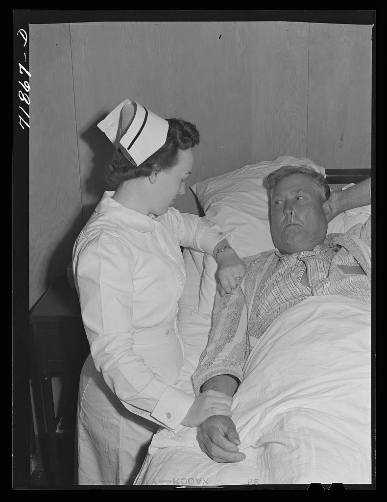 A nurse takes the temperature of a patient in a farm workers community hospital