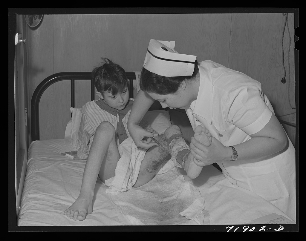 A nurse carefully removes a patient's bandage in a farm workers community hospital in Arizona