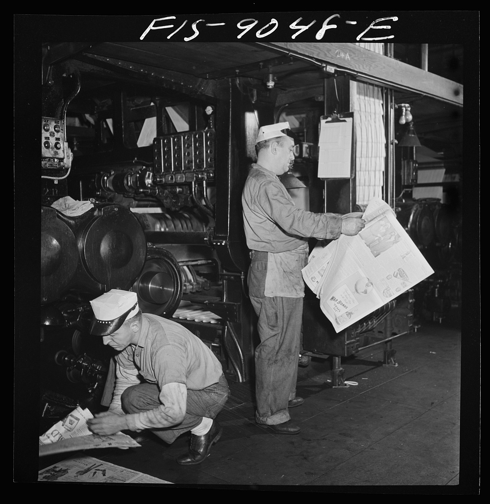 Pressmen check freshly printed newspapers as the presses run