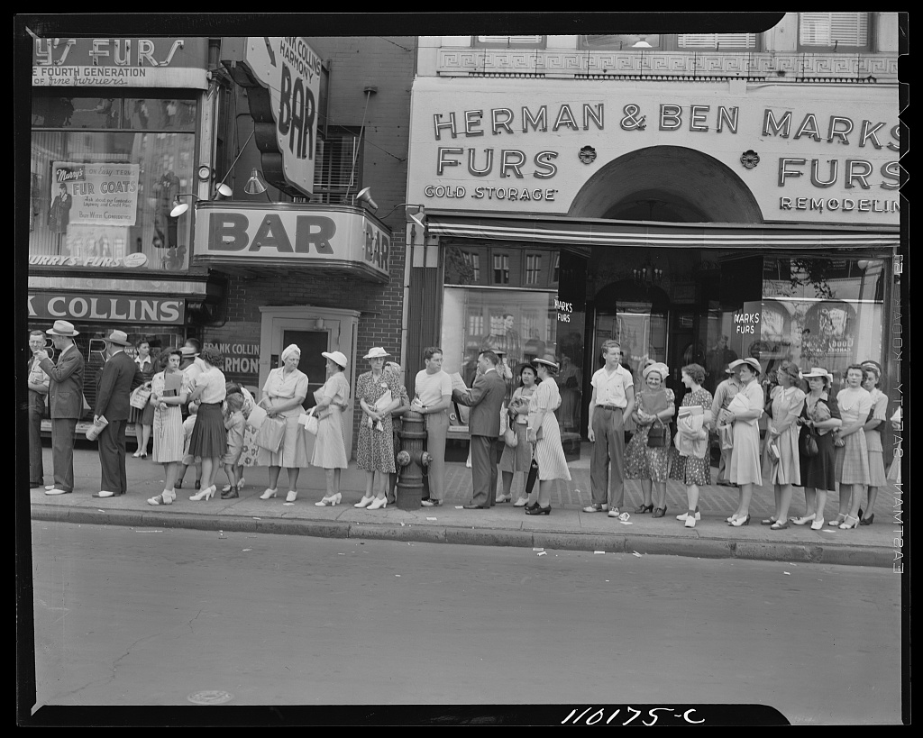 Workers lined up on a Detroit sidewalk waiting for a bus at the end of a shift