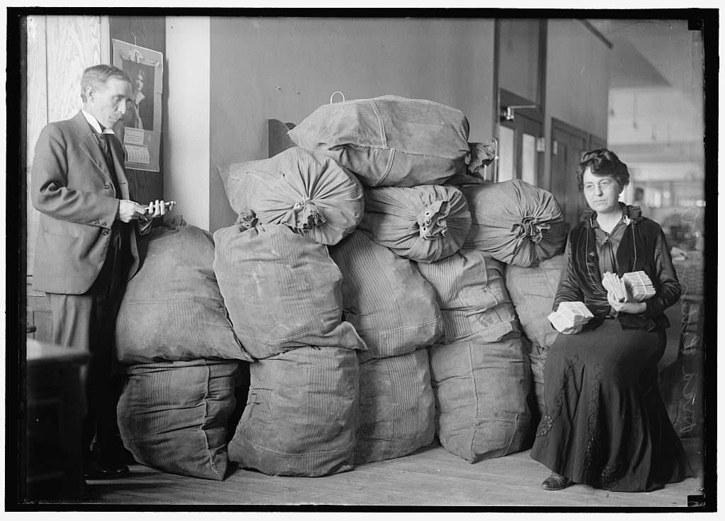 Postal clerks among stacked mail sacks at a sorting office