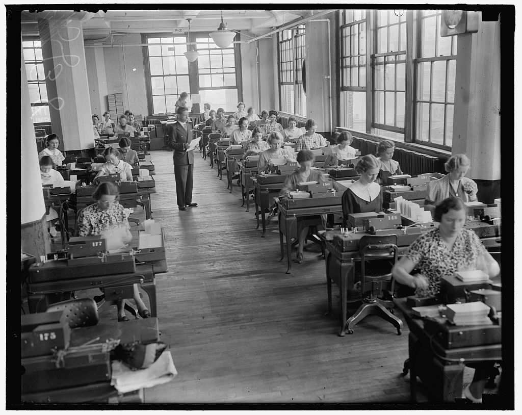 Rows of clerks at keypunch machines in a government records office