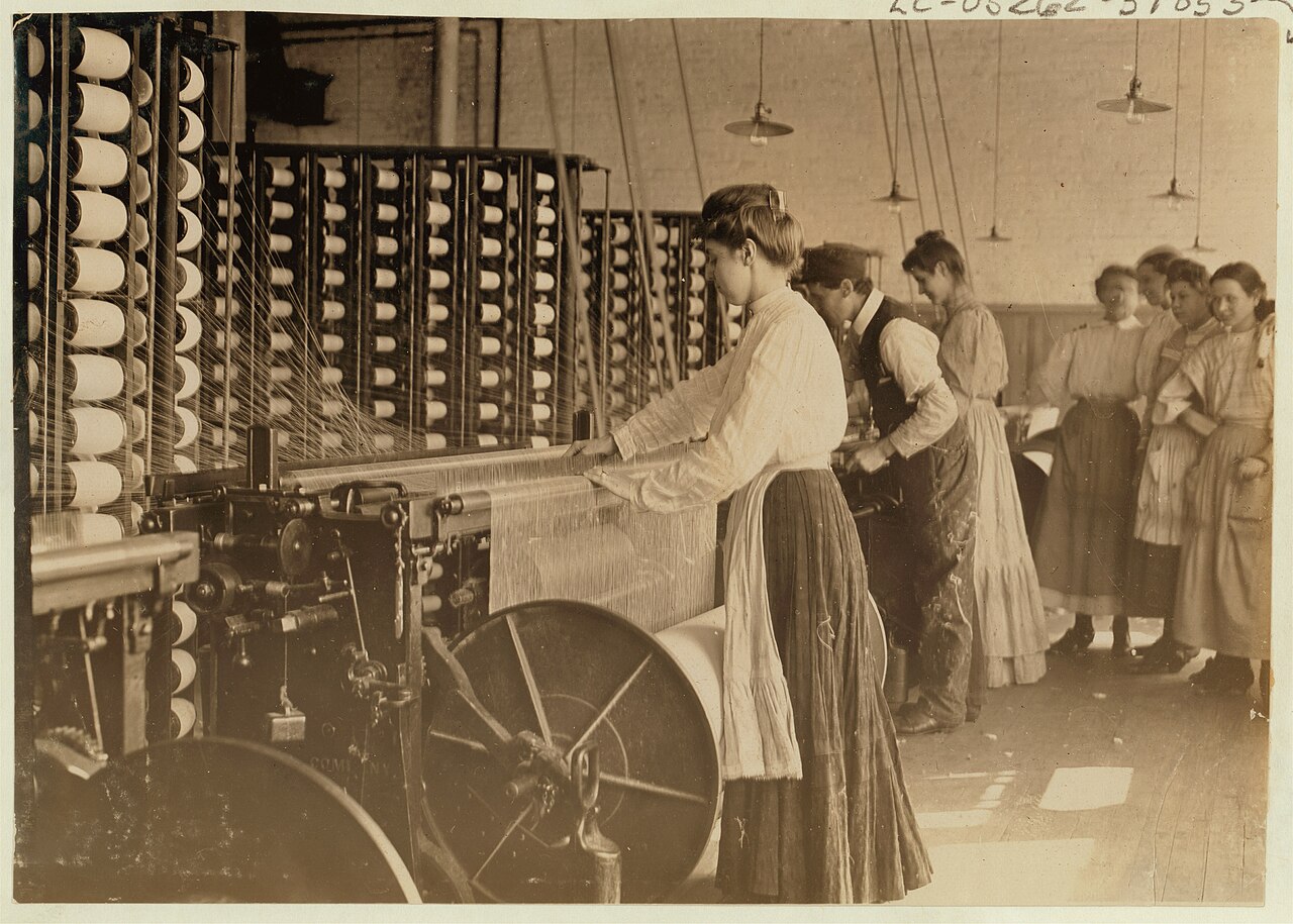 Young workers tending rows of spinning machines on a cotton-mill floor