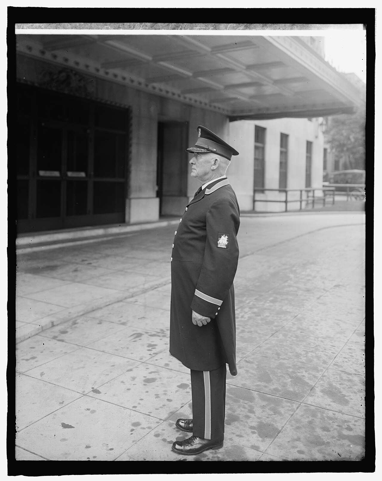 A uniformed doorman stands at the entrance of a grand hotel