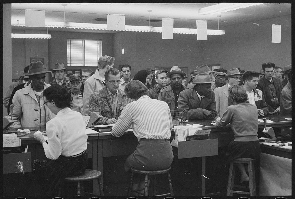 A crowd of men waiting at the counter of an unemployment office
